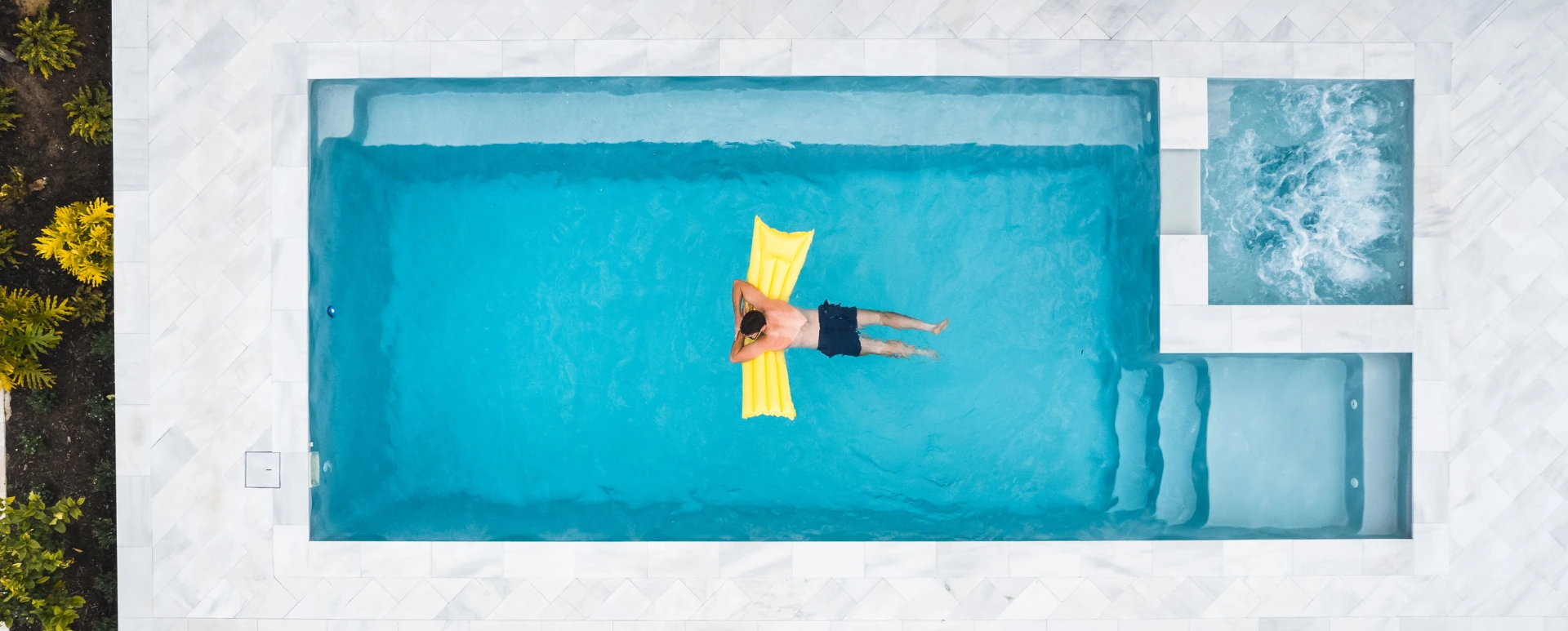 Man relaxing, swimming in the swimming pool in his own backyard.